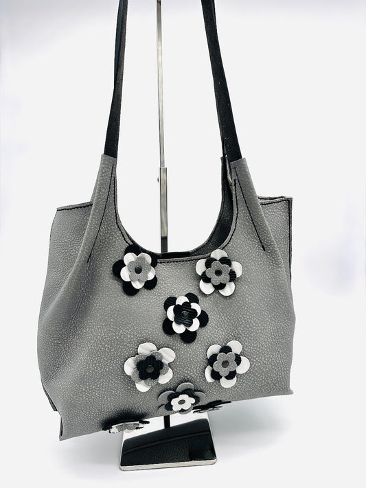Gray leather handbag with floral appliqués on a white background