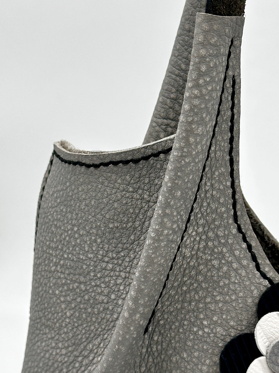 Close-up of a gray textured bag with a strap on a light gray background