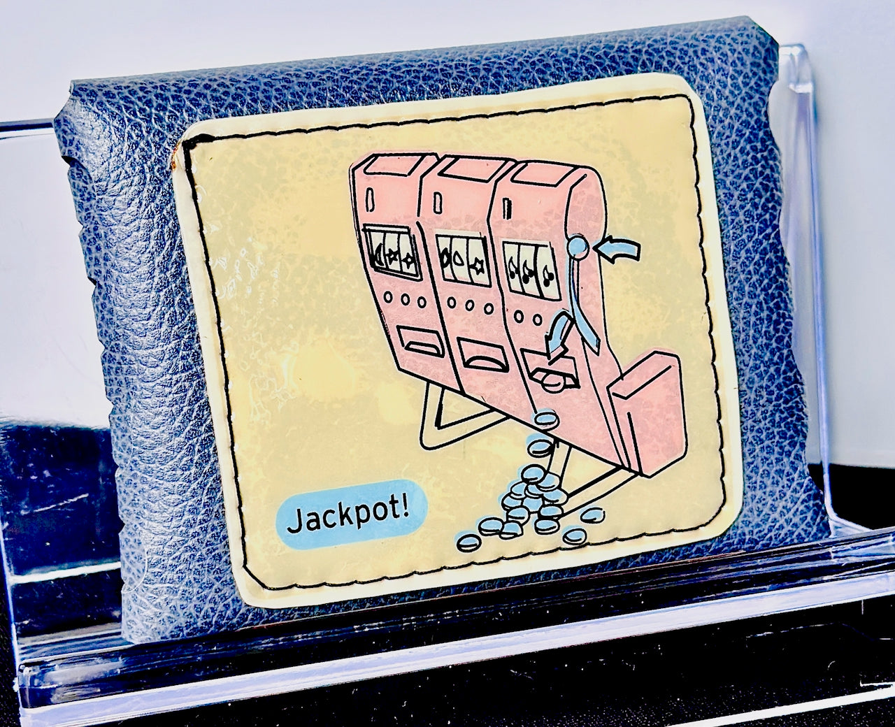 Blue leather wallet with a cartoon slot machine design featuring the word 'Jackpot!'.