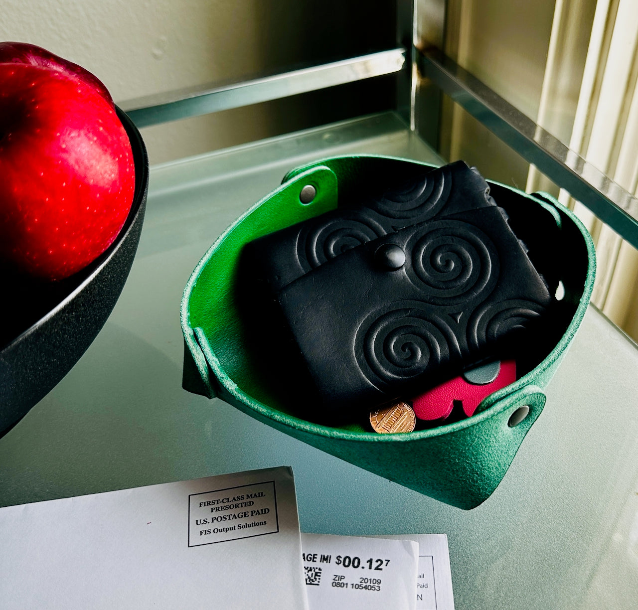 Green leather basket with black leather wallet in it.
