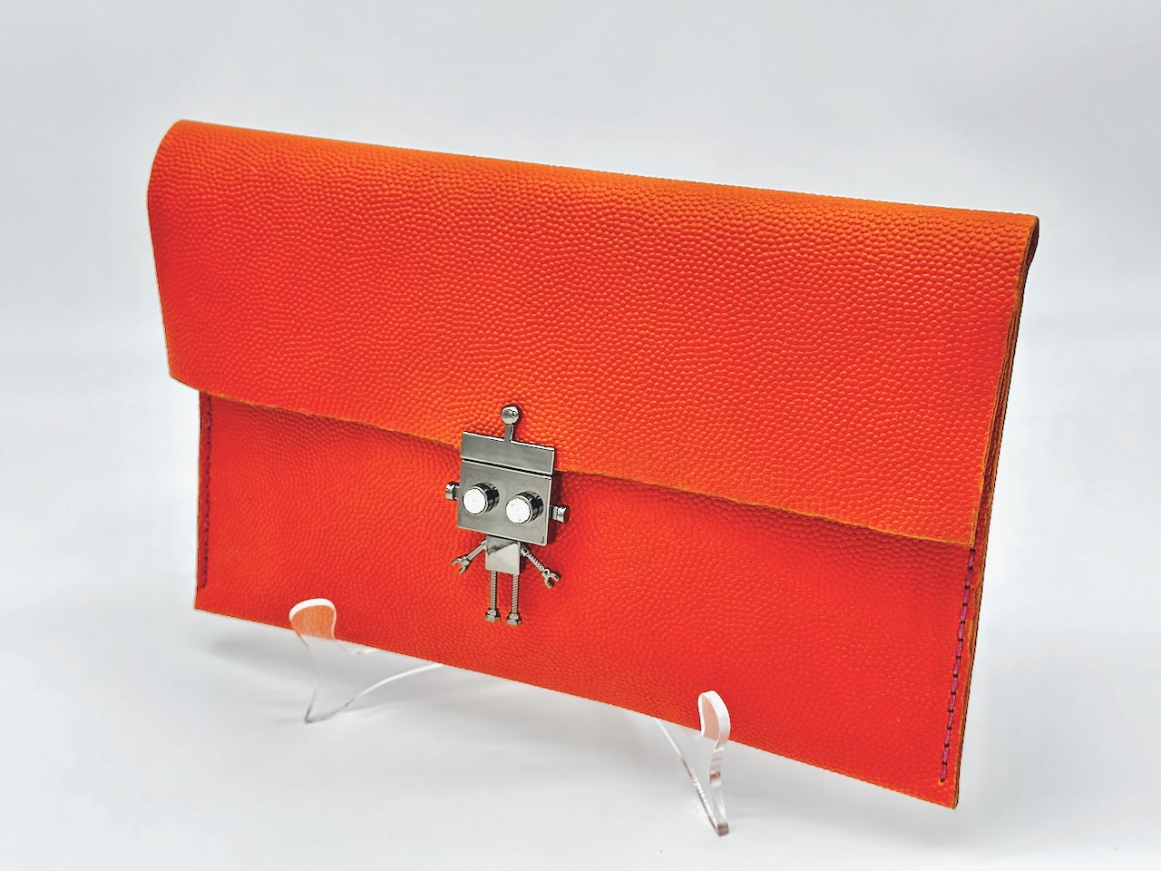 Orange clutch bag with a robot clasp on a white background