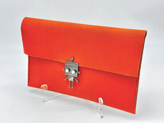 Orange clutch bag with a robot clasp on a white background