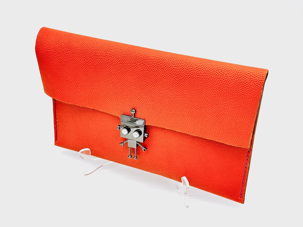 Orange clutch bag with a robot clasp on a white background