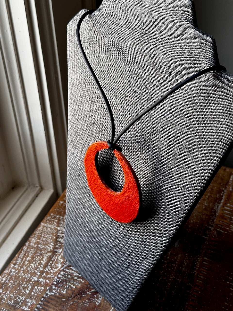 Orange pendant necklace on a gray fabric background