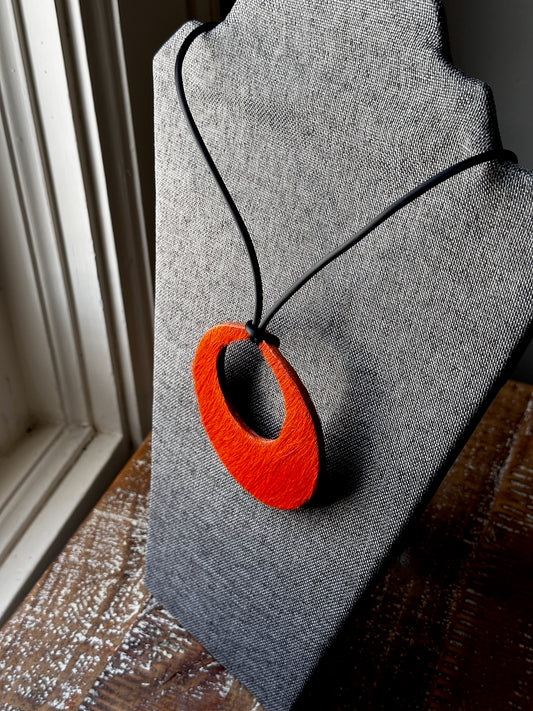 Orange pendant necklace on a gray fabric background