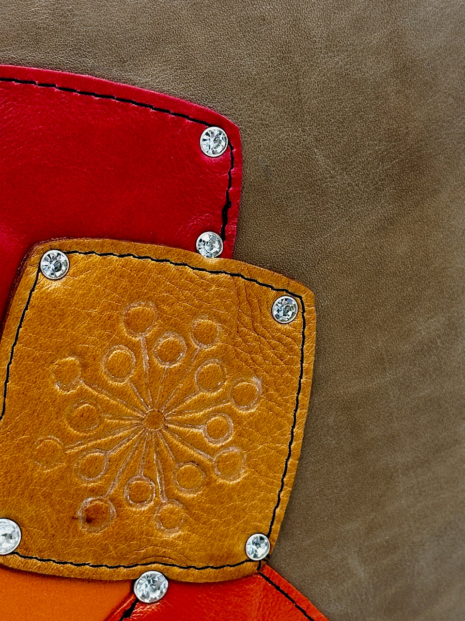 Close-up of a leather patch with intricate design and red border on a brown background