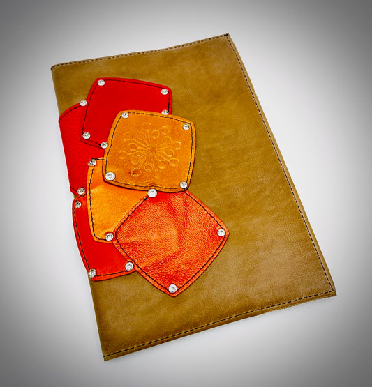 Tan leather notebook with red and orange patches on a gray background