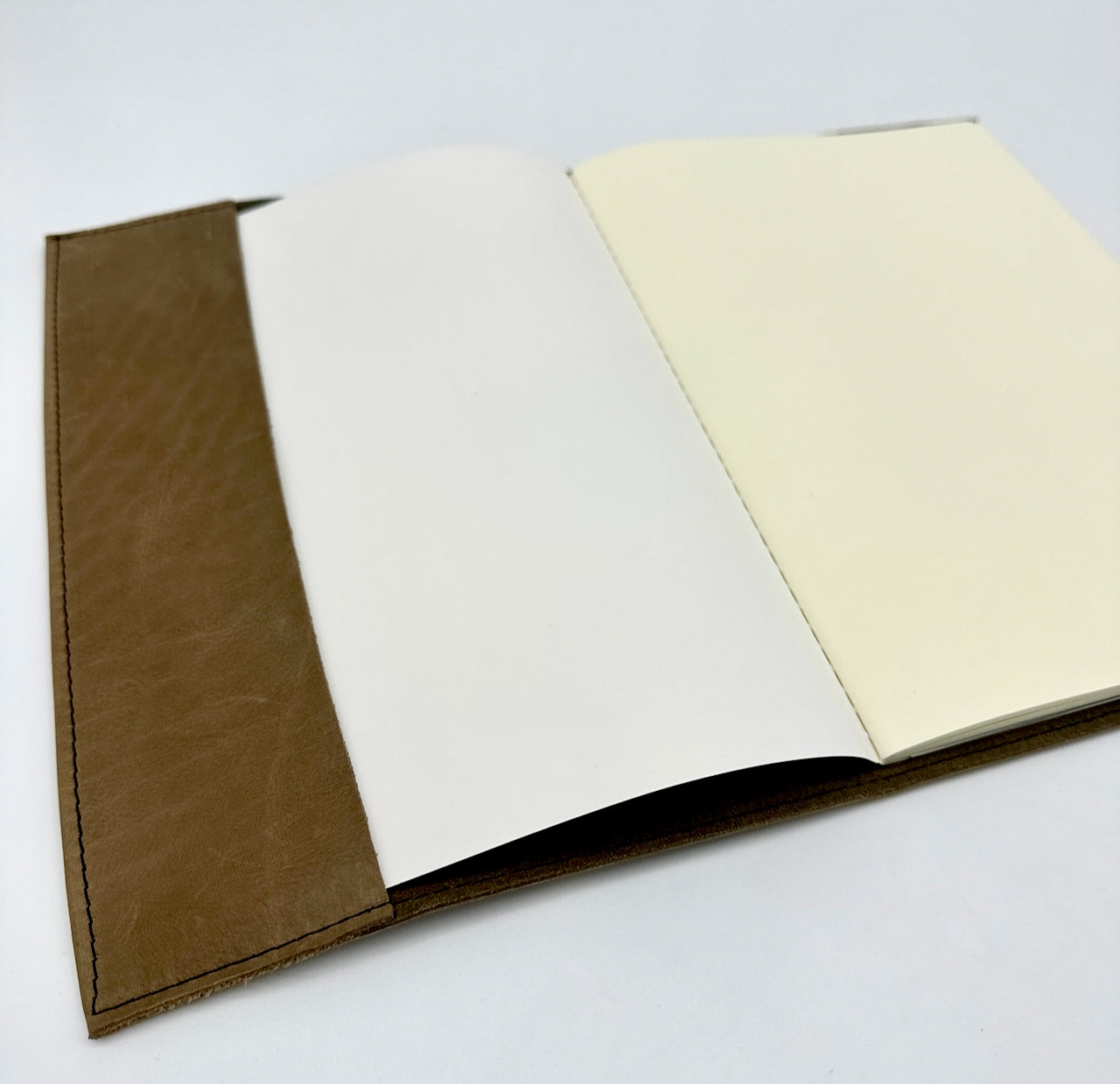 Open notebook with brown leather cover and cream pages on a white background