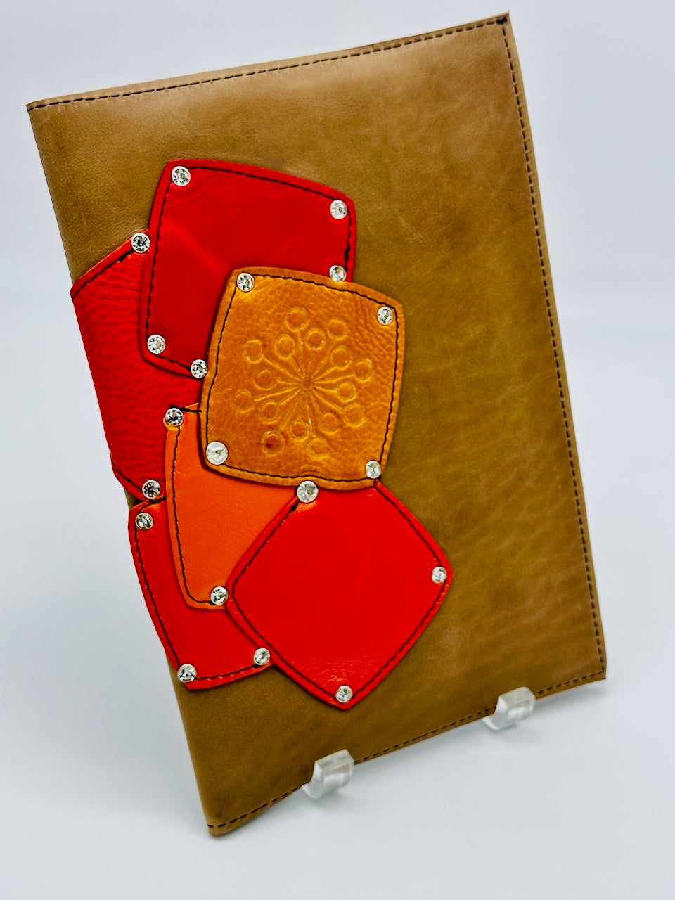 Tan leather cover with red and orange geometric patches on a white background