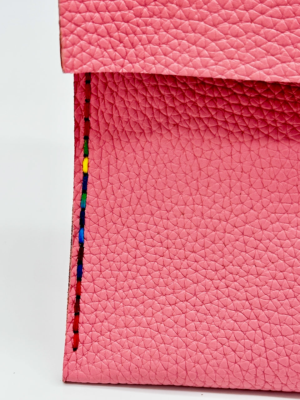 Close-up of pink leather with colorful stitching on a white background
