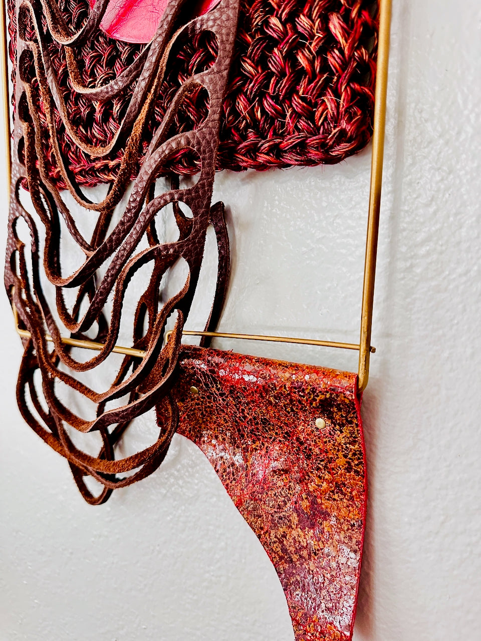 Decorative wall art with wavy leather design and red and gold finish on a white background