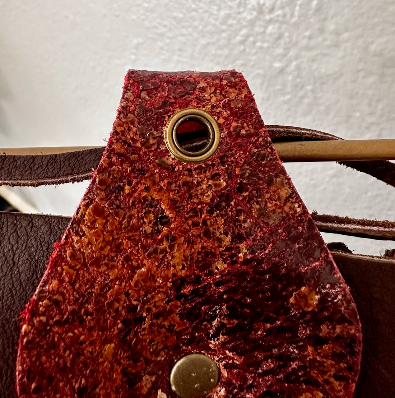 Close-up of a eyelet on a brown leather wall hanging with a white background