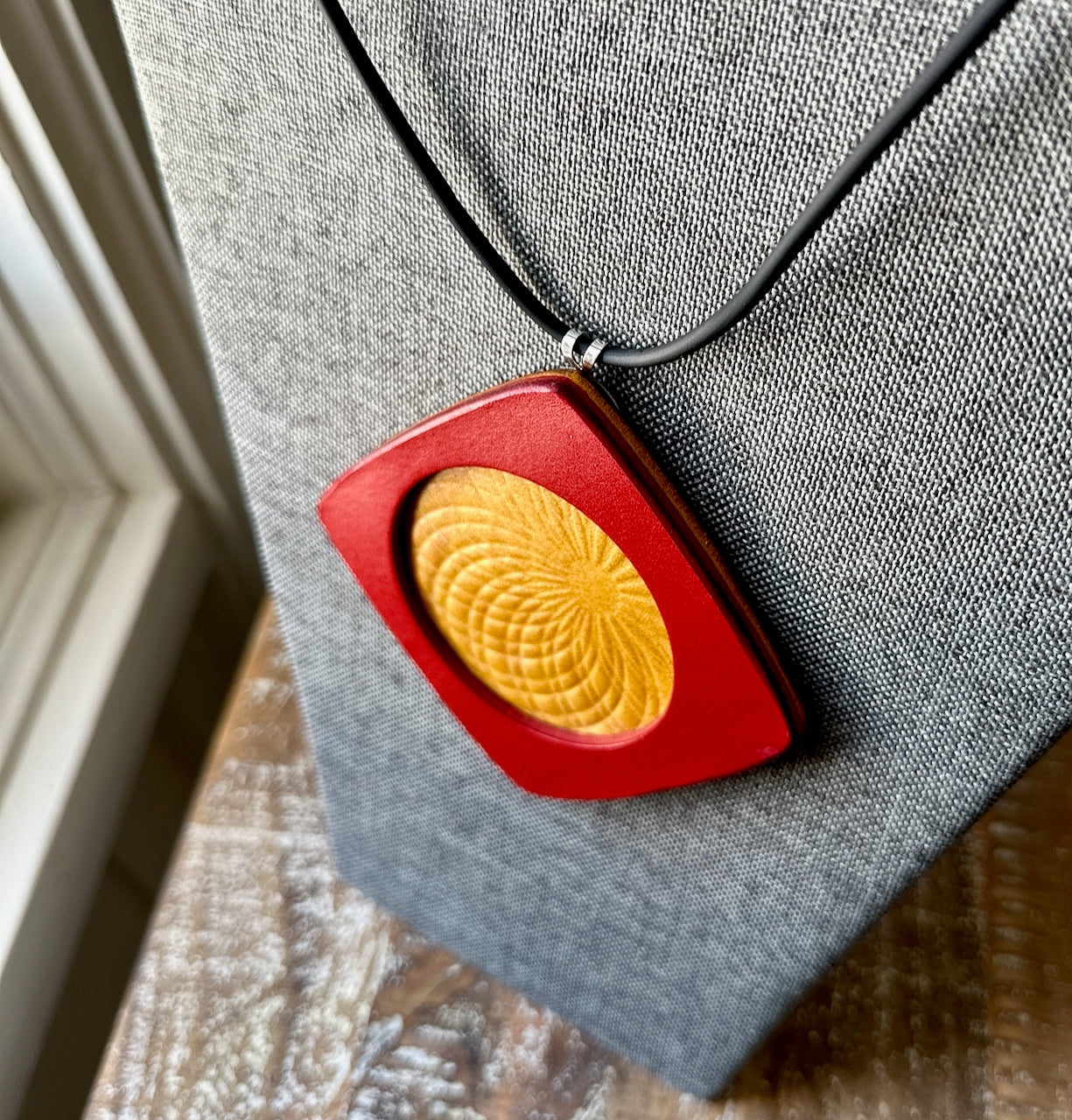 Red and yellow leather pendant on a gray fabric background