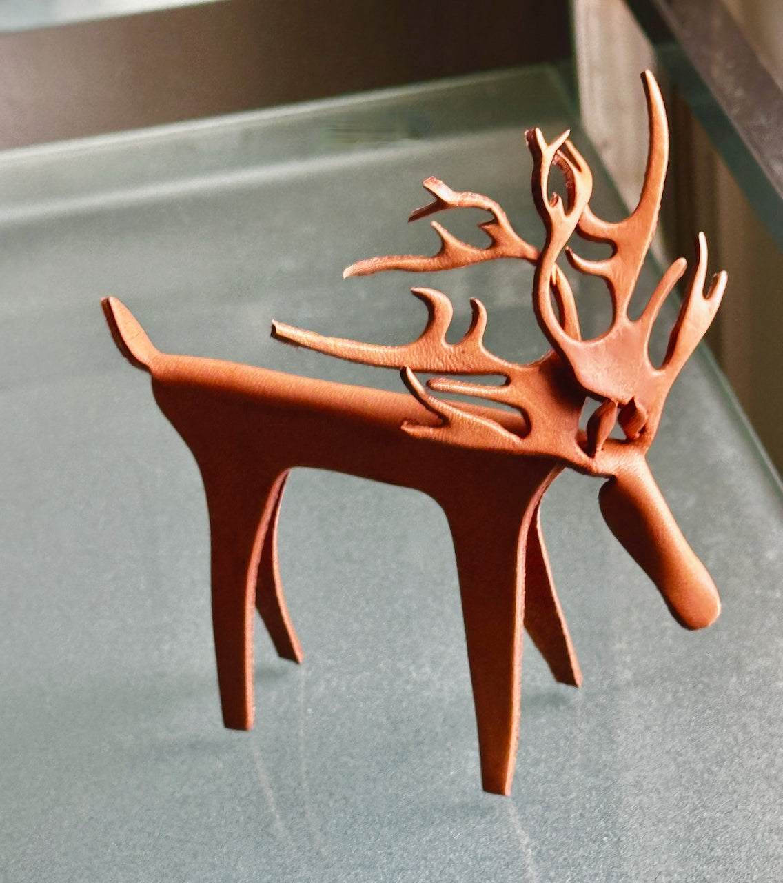 Leather reindeer sculpture with antlers on a glass shelf