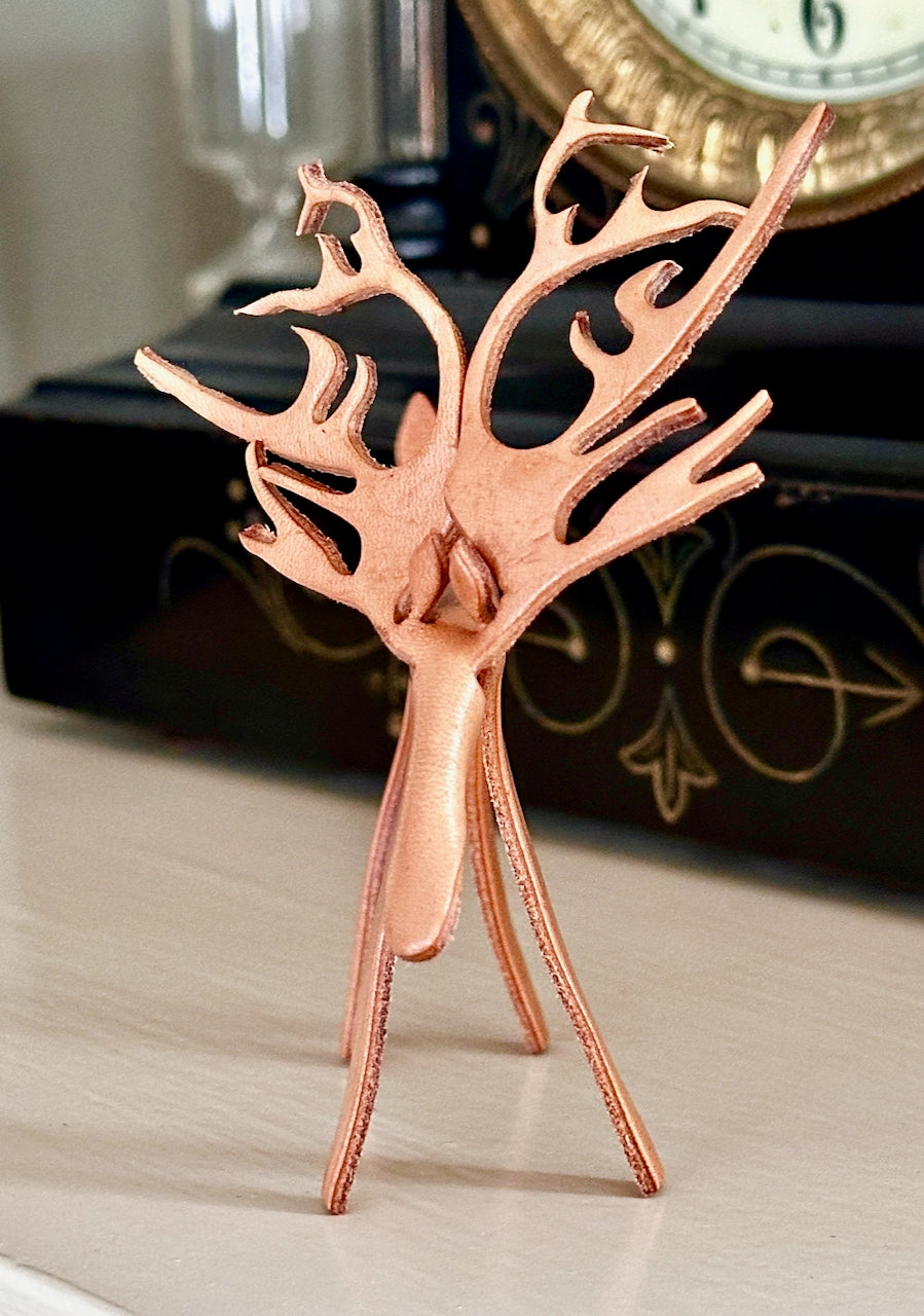 Leather reindeer figurine on a wooden surface with a blurred background