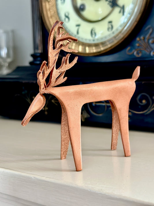 Leather deer figurine on a mantel with a clock in the background