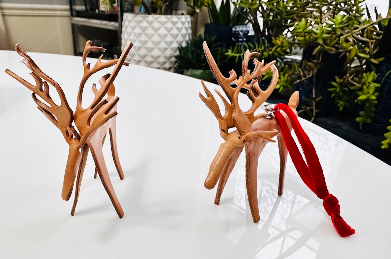 Leather reindeer figurines with a red velvet loop on a white surface