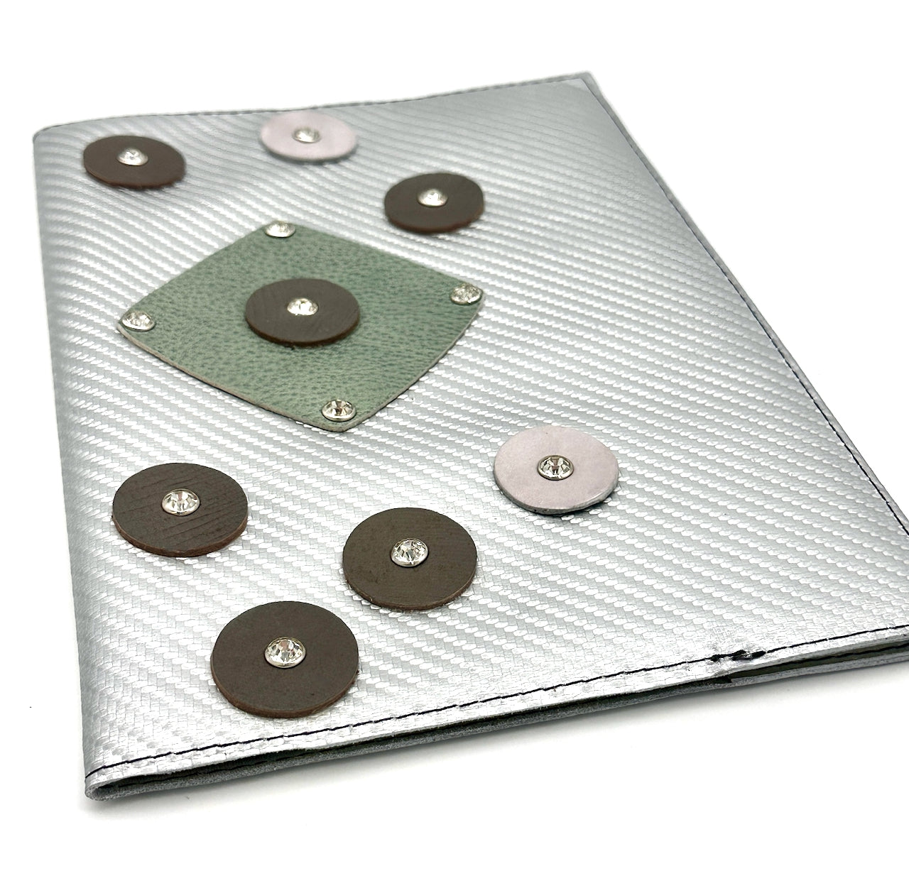 Silver notebook with decorative circle leather accents and rhinestone rivets on a white background