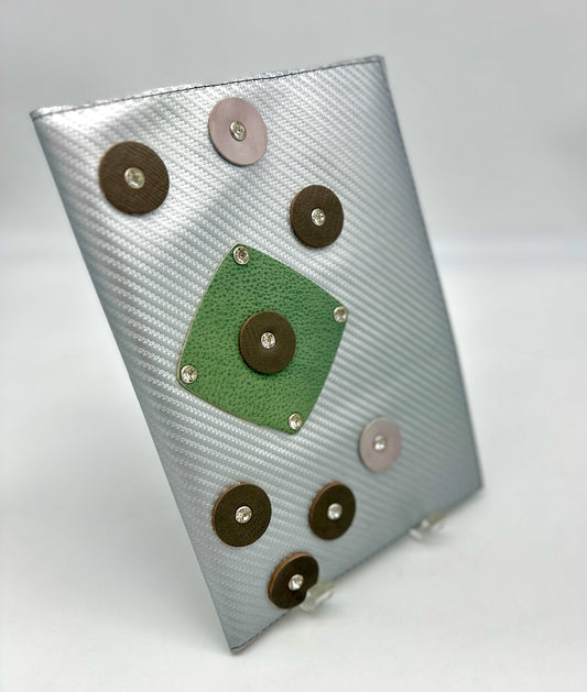 Silver leather journal with decorative leather circles on a white background