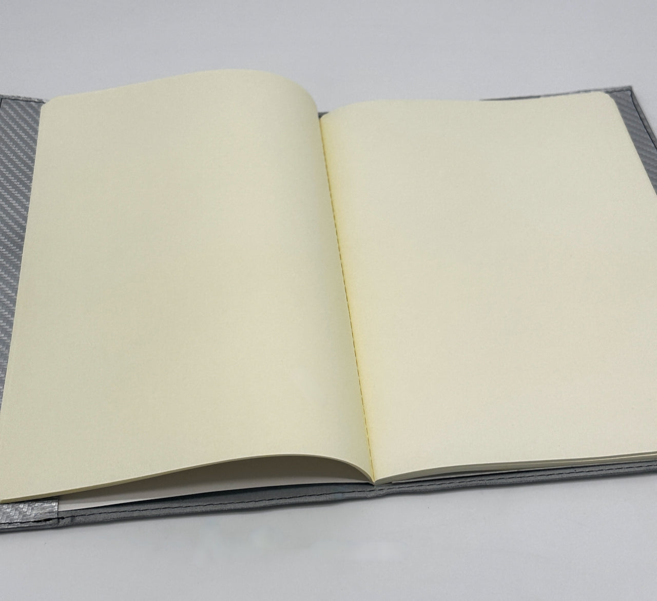 Open notebook with gray cover and off white blank pages on a light gray background