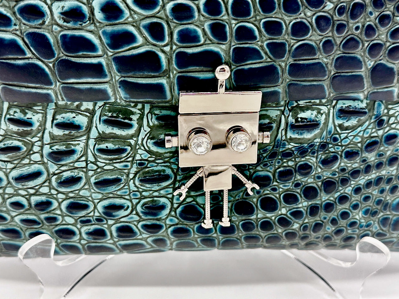 Metallic robot clasp lock on a textured blue green leather purse