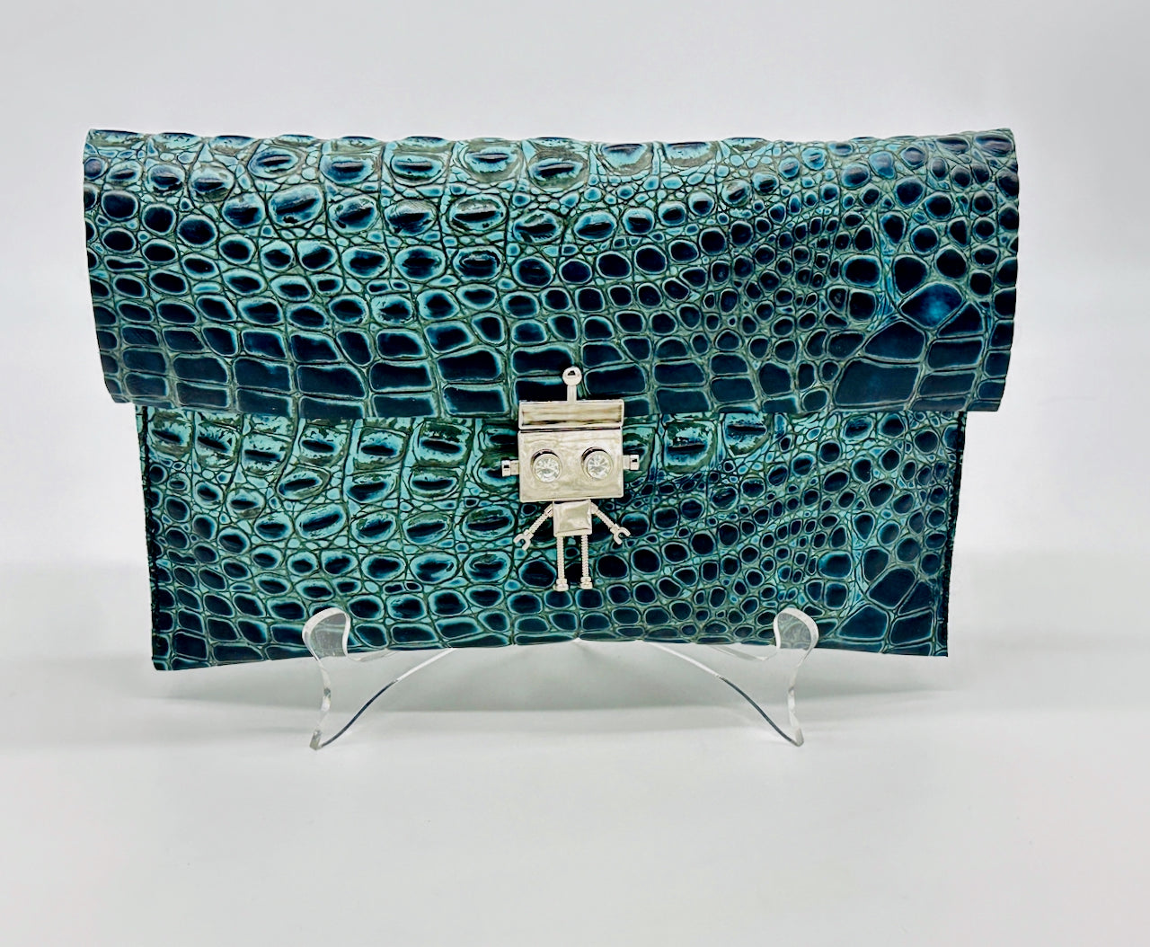 Teal and black croco print clutch leather bag with robot clasp on a white background