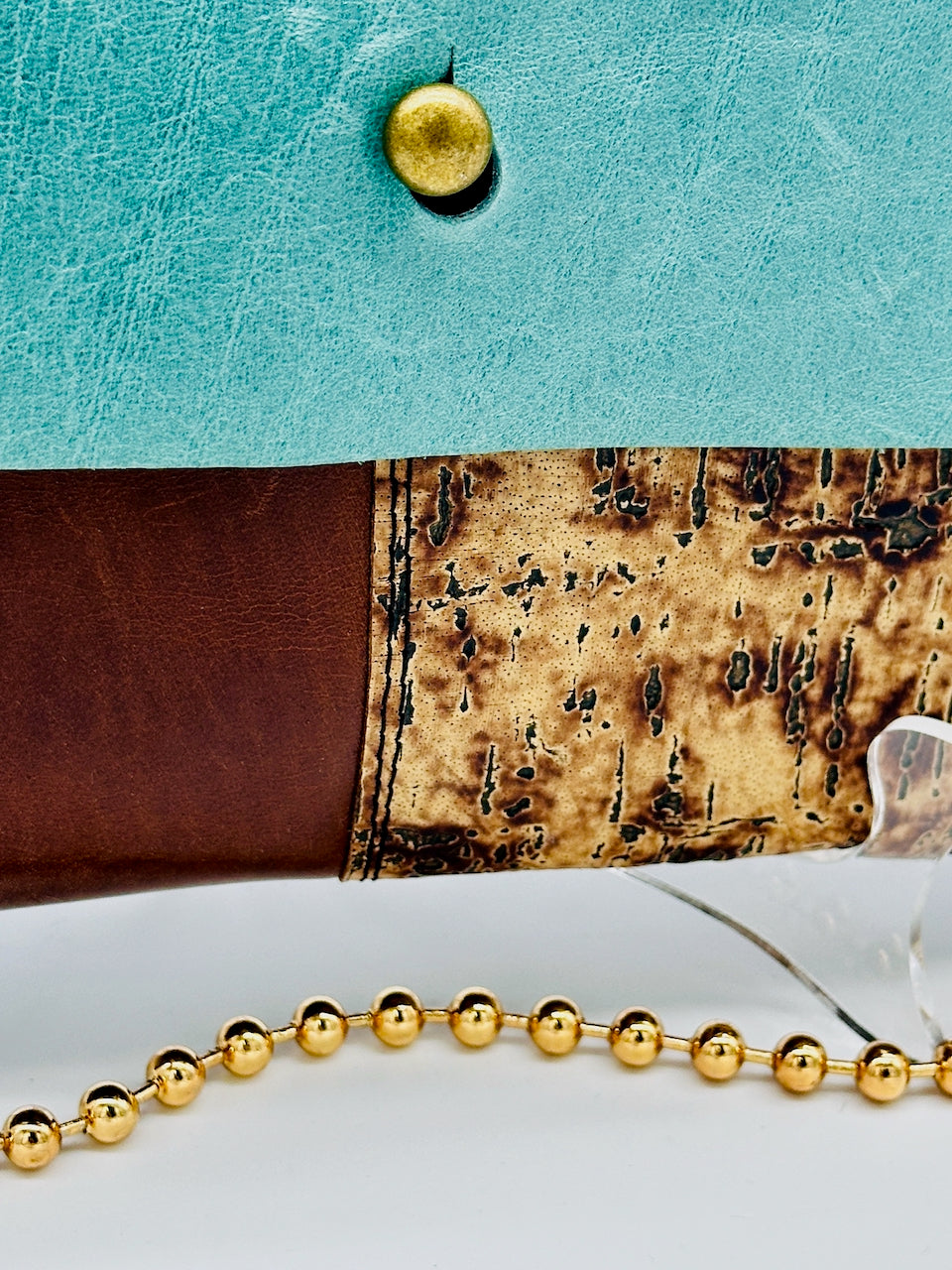 bottom detail of leather purse featuring blue, brown and cork leather