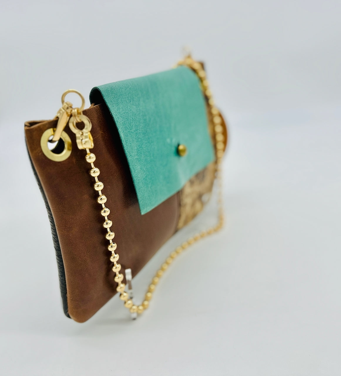 soft focus leather purse at angle with gold ball chain strap and gold grommet.