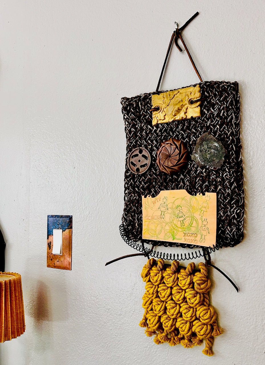 Decorative wall hanging art with textured elements on a white wall