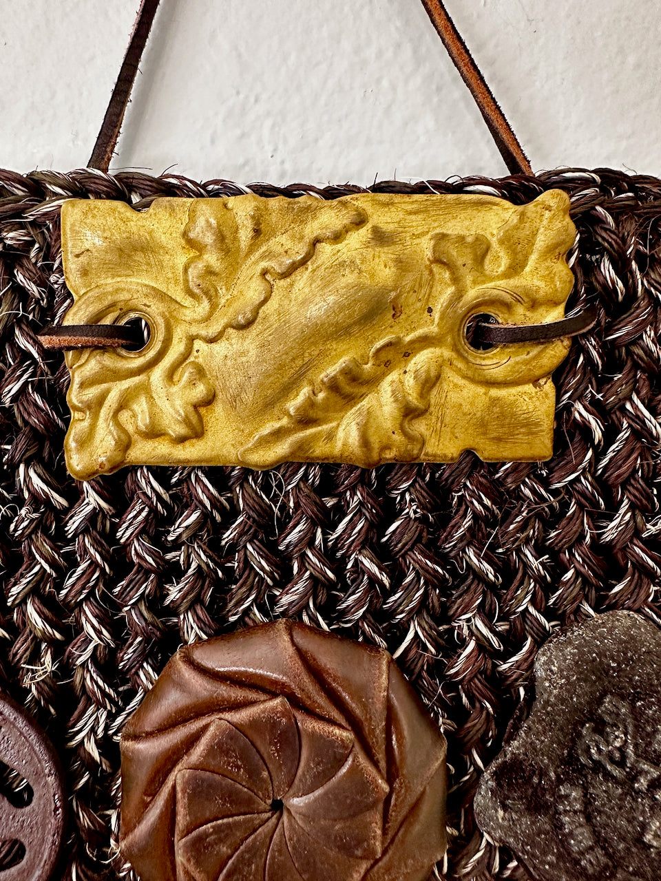 Decorative object with gold metal piece and textured brown elements on a textured background