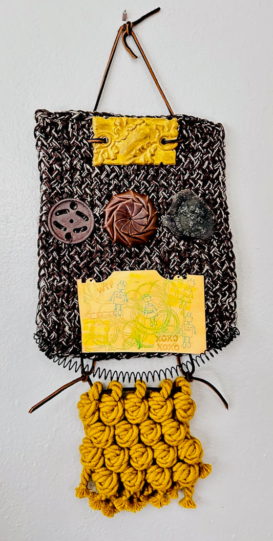 Textile art piece by Undercover Popular Leather Goods with woven patterns and colorful elements on a gray background