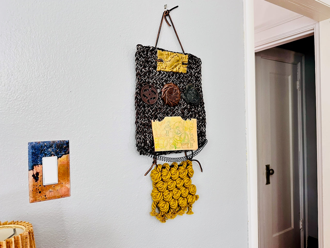 Decorative wall hanging with geometric patterns on a white wall.