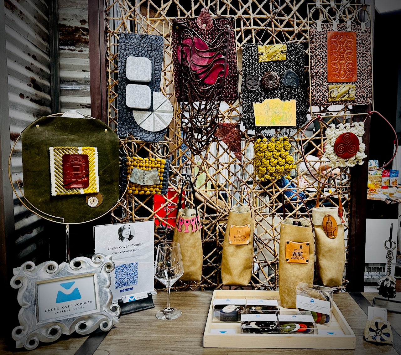 Large display of wall hangings and four leather wine bottle carriers on table