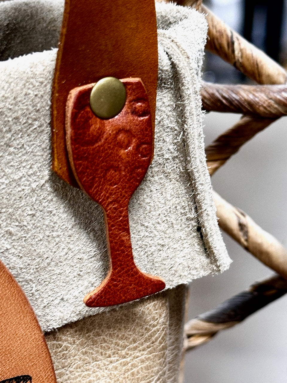 textured leather wine glass shape riveted to bottle carrier strap