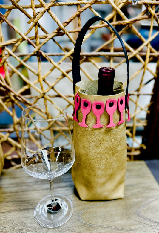 Leather wine bottle carrier sites on table next to a wine glass