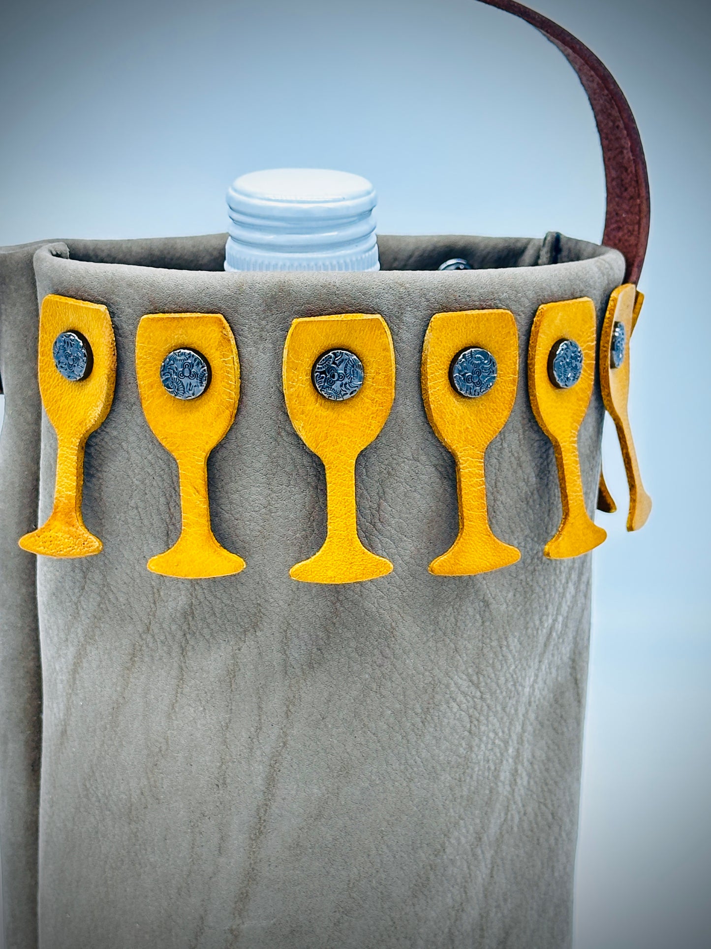 Beige leather wine bag with yellow wine glass-shaped pockets on a gray background