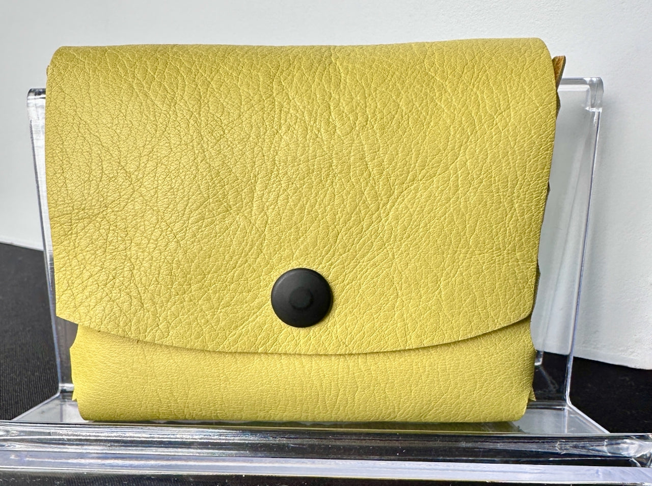 Yellow leather wallet with a black snap closure.