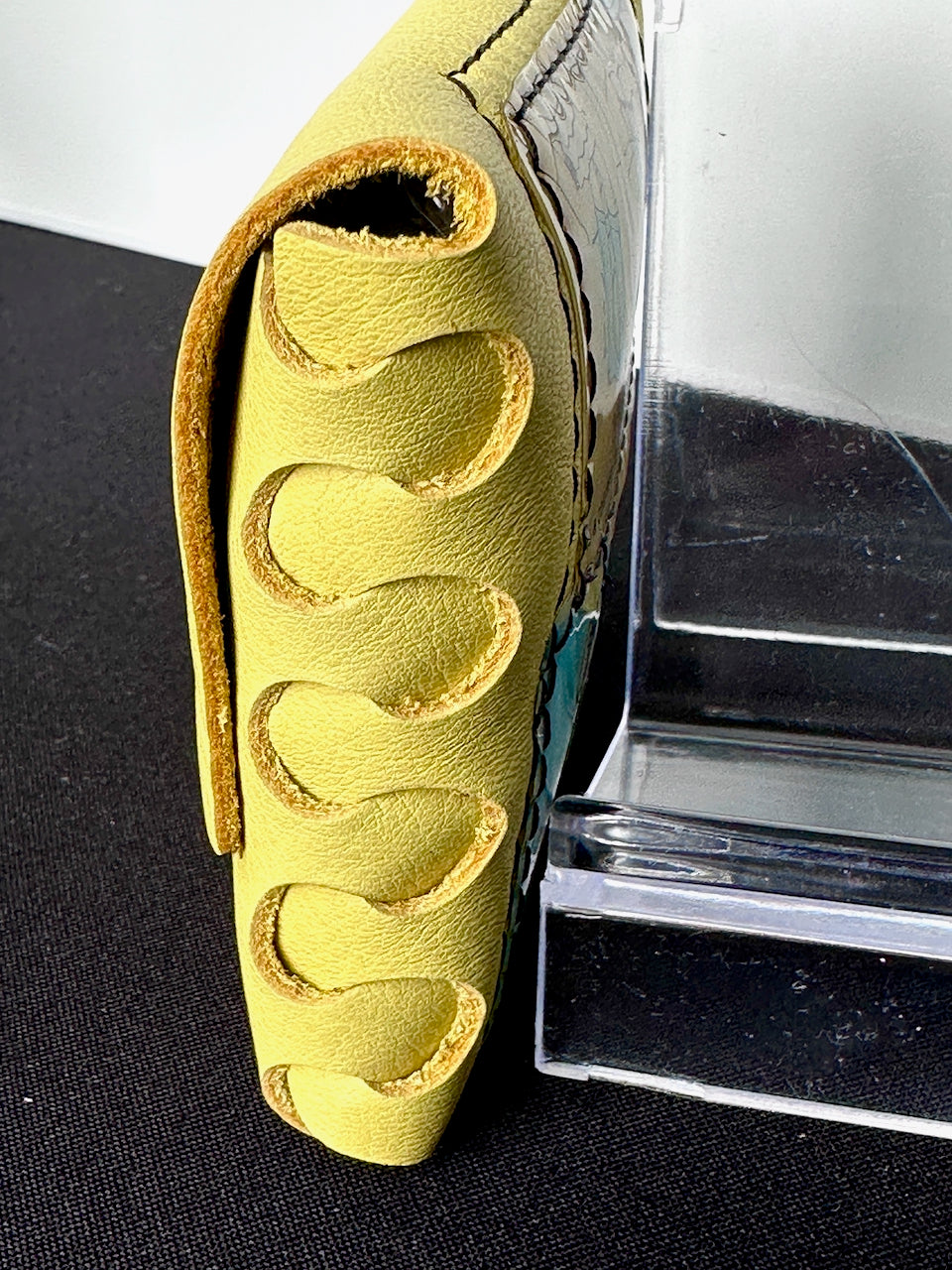 Close-up of a yellow leather wallet with an interlocked side seam
