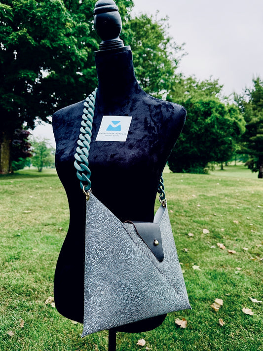 Greenish leather shagreen handbag with a pea green matte acrylic chain strap on a mannequin torso outdoors.