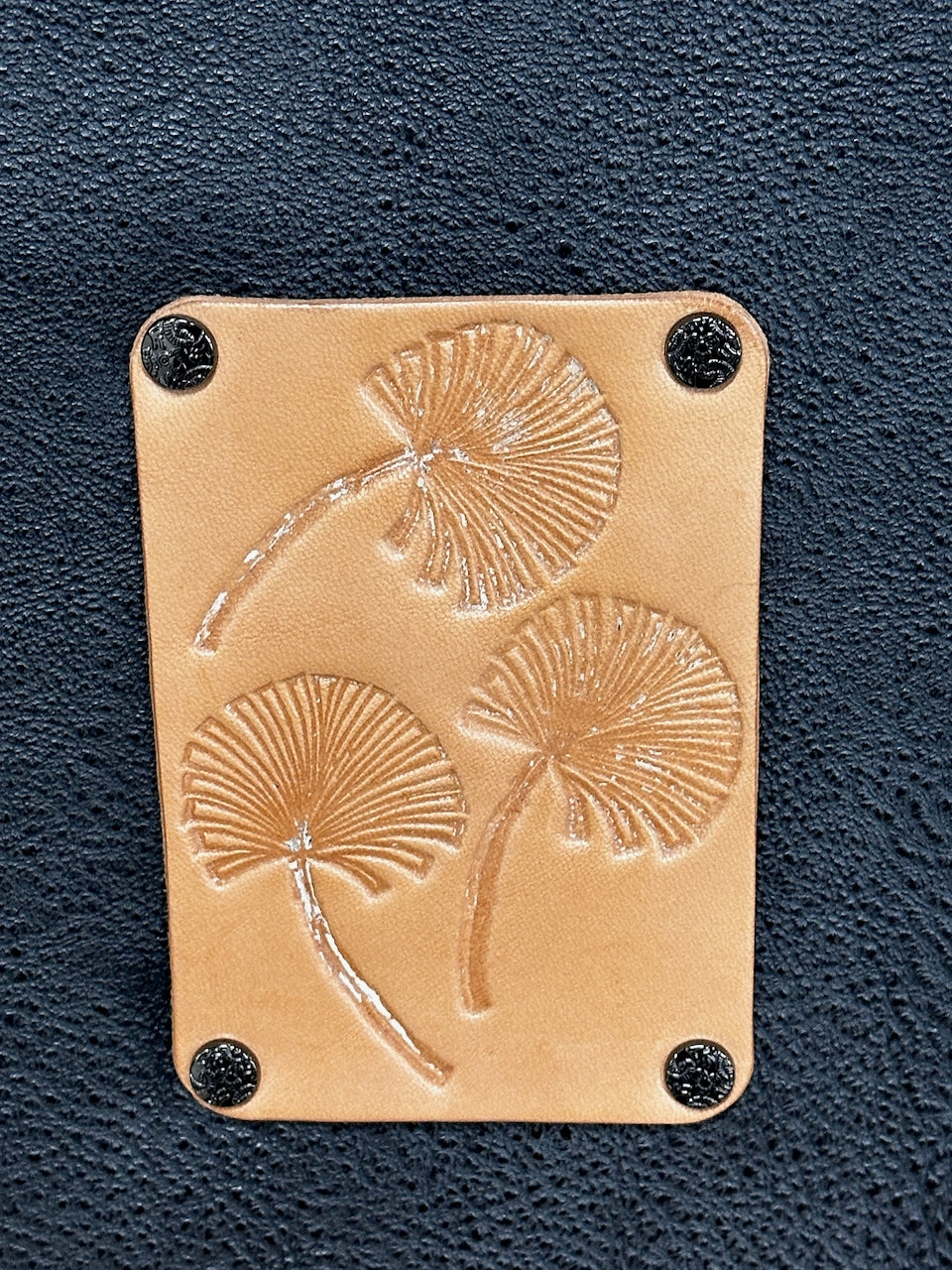 Leather patch with floral embossing on a dark black background