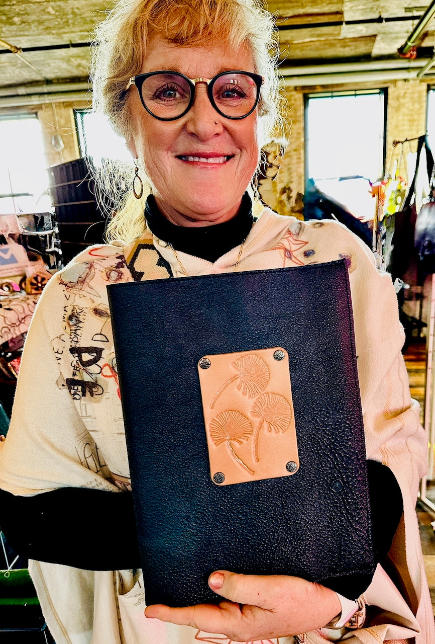 Woman holding a black leather-bound book with a decorative floral flap.
