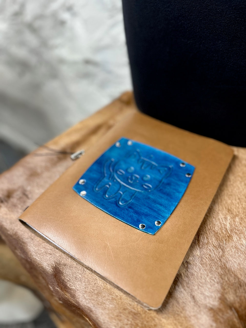 overhead angle of brown and blue leather journal with a kitten on the front cover