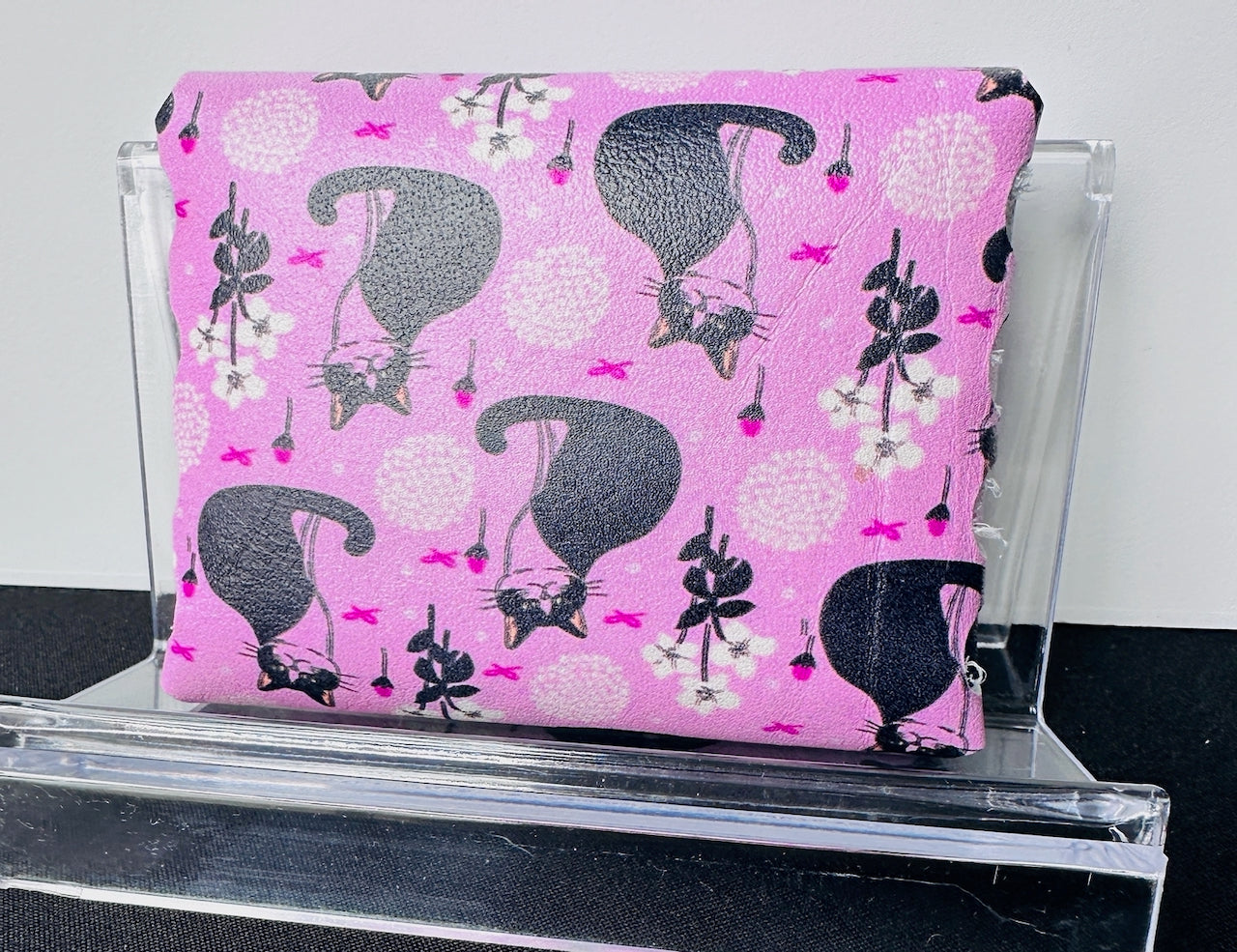 Back of leather wallet featuring black and white cats on a pink background.