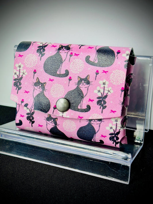 Pink wallet with cat pattern on a clear stand