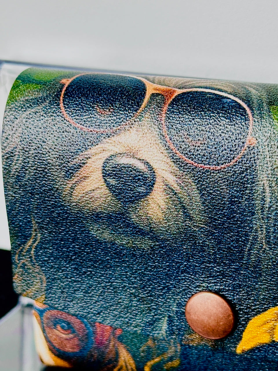 Close-up of a leather wallet with a dog's face and sunglasses design.