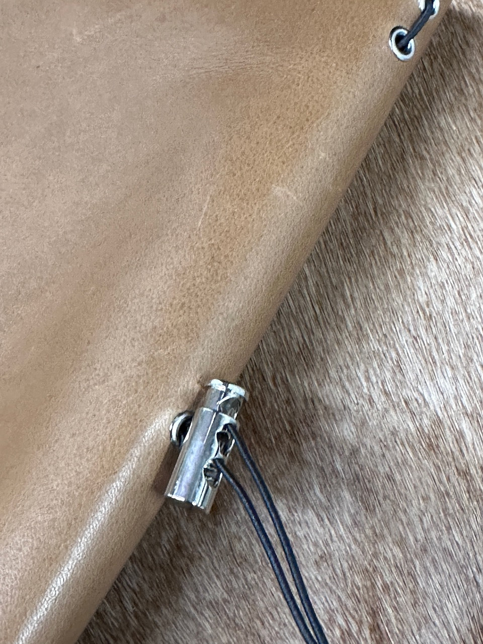 detail of spine of leather journal with toggle so you can refill the paper pages