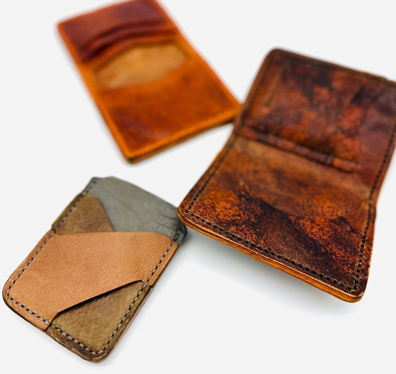 Three leather card holders and wallets on a white background